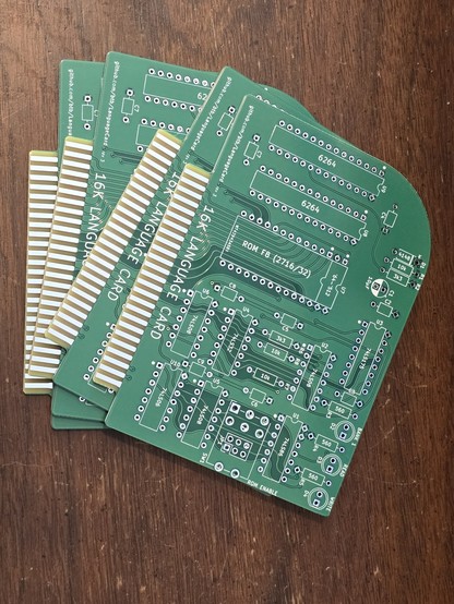 stack of 4 PCBs for an Apple II/II+ language card sitting on a wooden background.