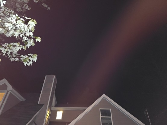 the top of a house is visible with a single purple streak coming from behind the house and leaving at the top right of the frame